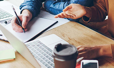 people writing together at desk